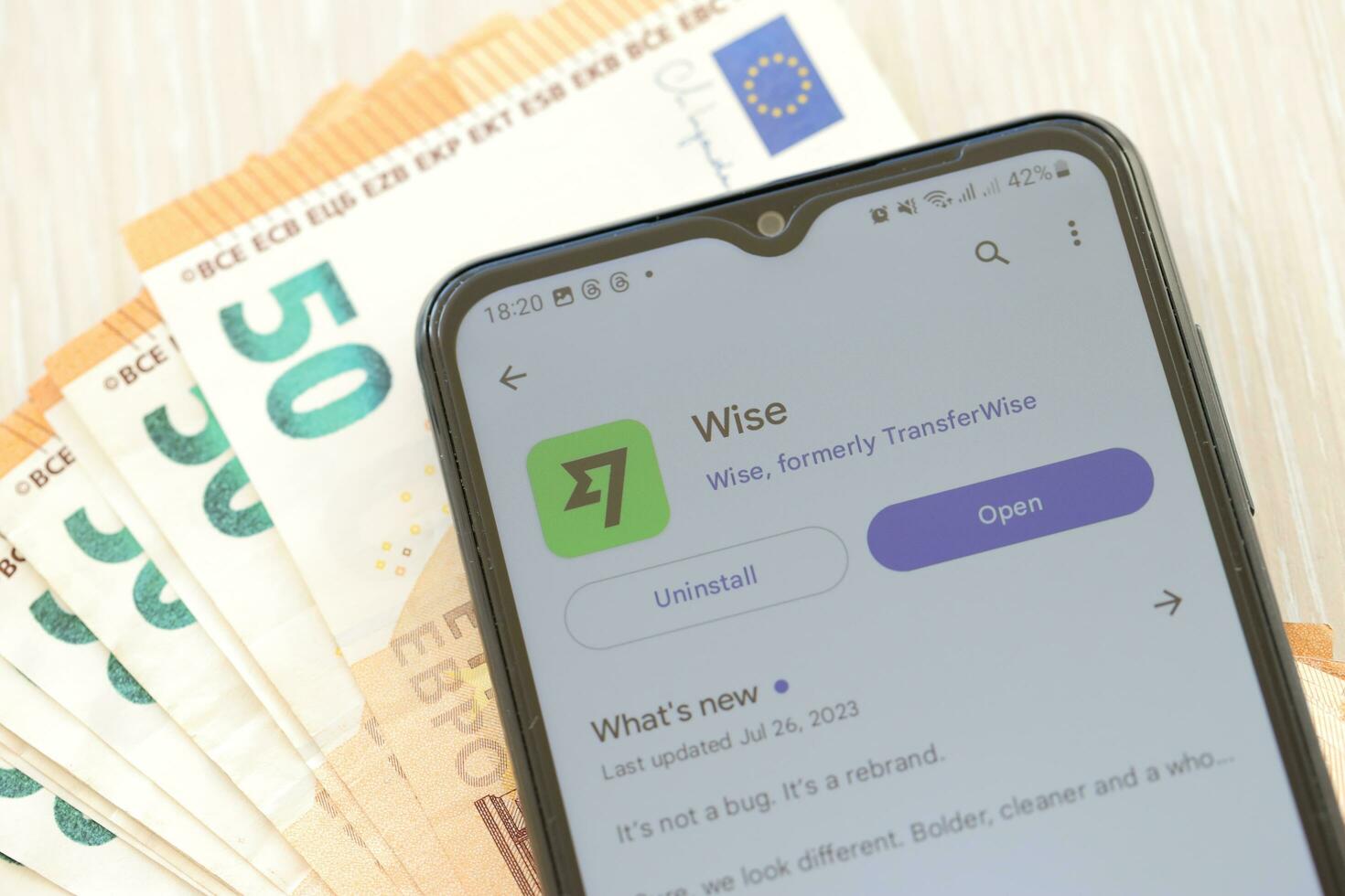 TERNOPIL, UKRAINE - AUGUST 3, 2023 Wise application on screen on modern smartphone and many bills of euro currency photo
