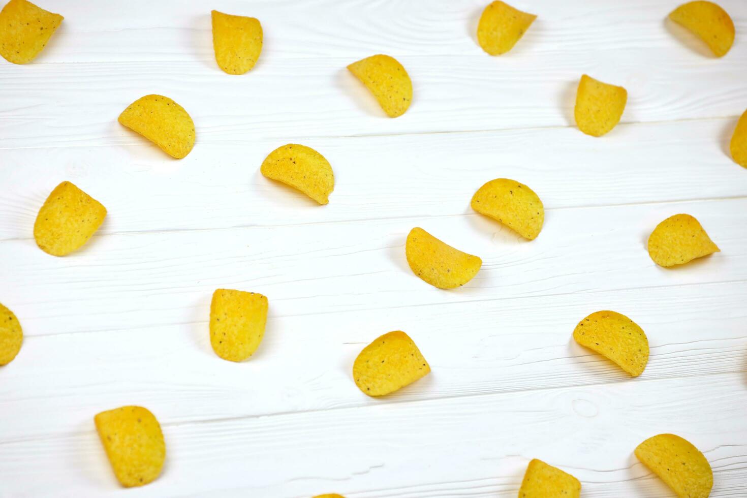 Many orange Pringles potato snack chips on white wooden table. Pringles is a brand of potato snack chips owned by Kellogg Company photo