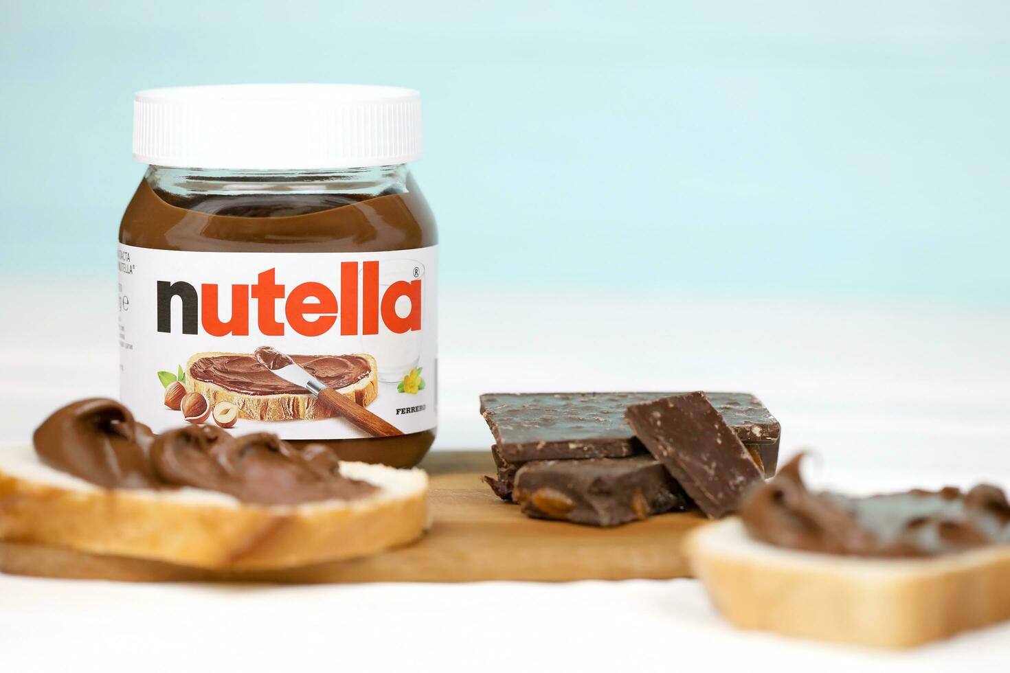 KHARKOV, UKRAINE - DECEMBER 27, 2020 Nutella glass can and spread on freshly baked bread. Nutella is manufactured by Italian company Ferrero first introduced in 1964 photo