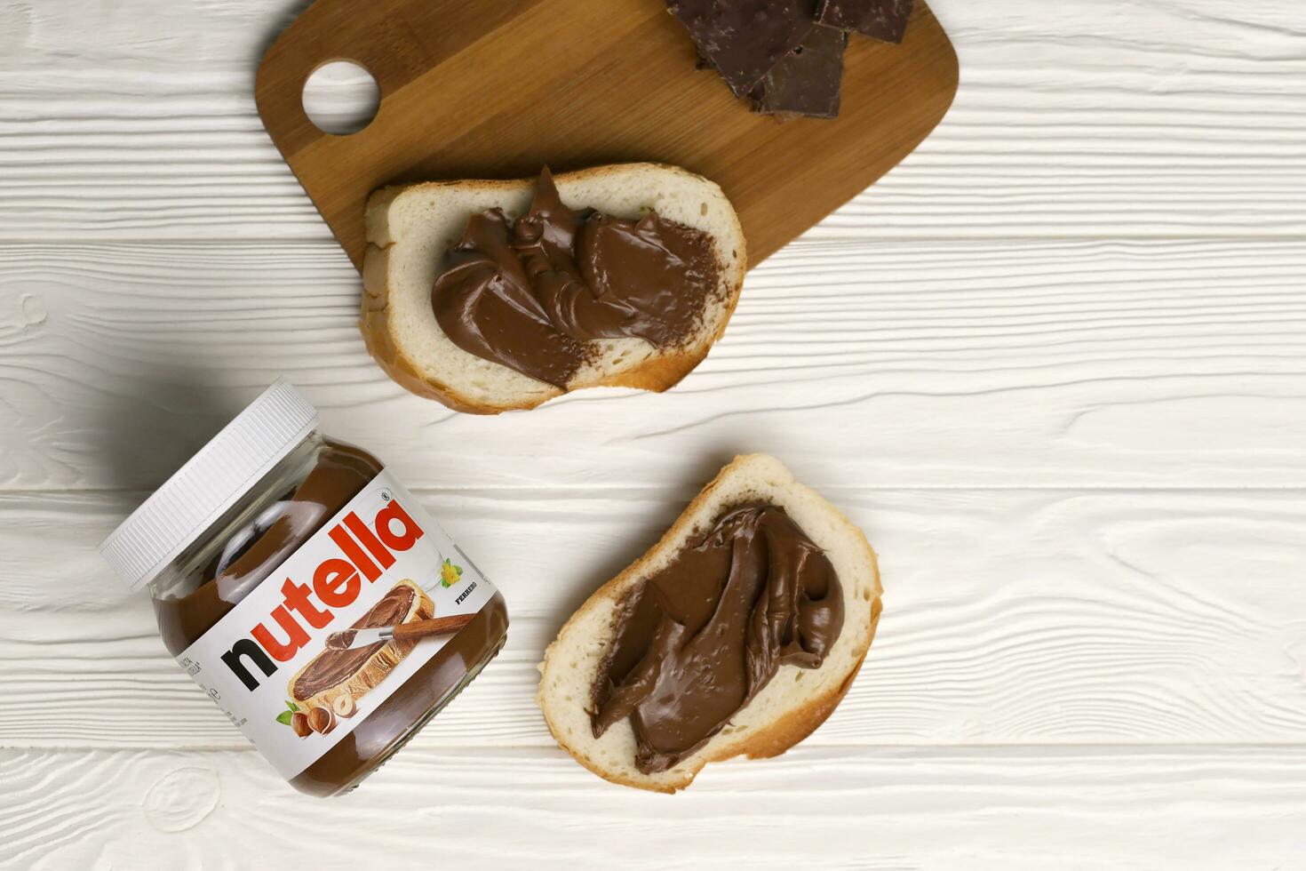 KHARKOV, UKRAINE - DECEMBER 27, 2020 Nutella glass can and spread on freshly baked bread. Nutella is manufactured by Italian company Ferrero first introduced in 1964 photo