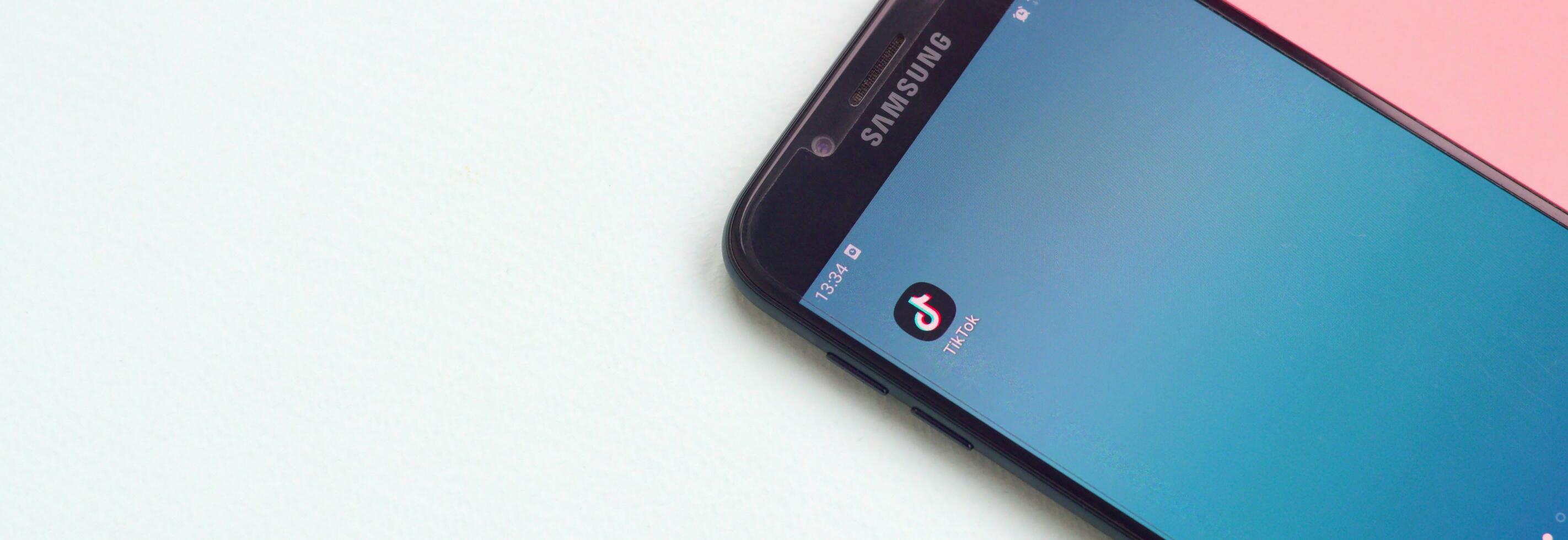 Tiktok application on samsung smartphone screen on pastel background. TikTok is a popular video-sharing social networking service owned by ByteDance photo