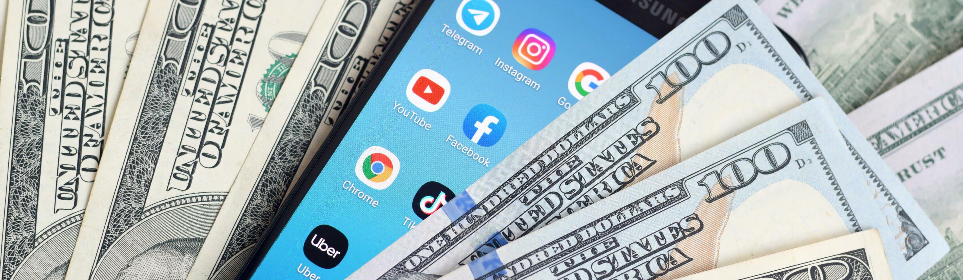 Smartphone screen with many popular apps and lot of hundred dollar bills. Business and social networking concept photo