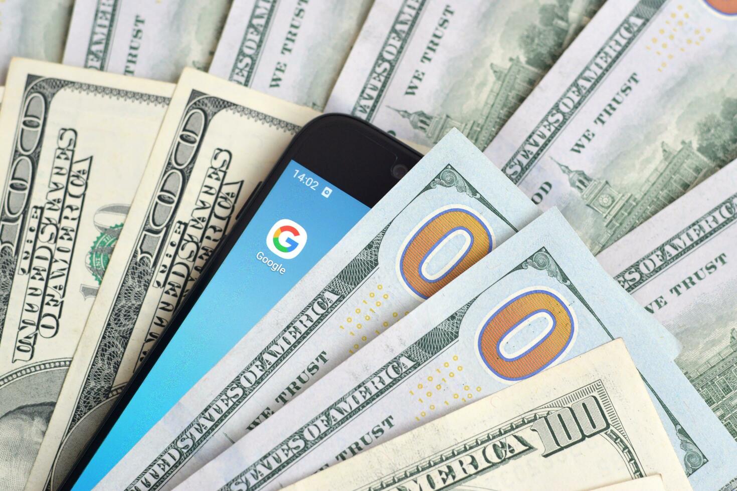 Smartphone screen with Google app and lot of hundred dollar bills. Business and social networking concept photo