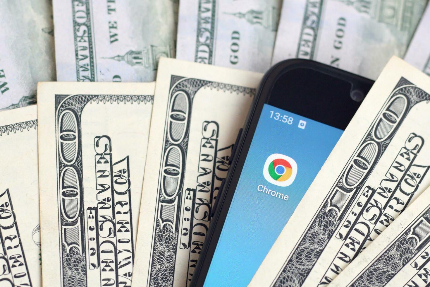 Smartphone screen with Google chrome app and lot of hundred dollar bills. Business and social networking concept photo