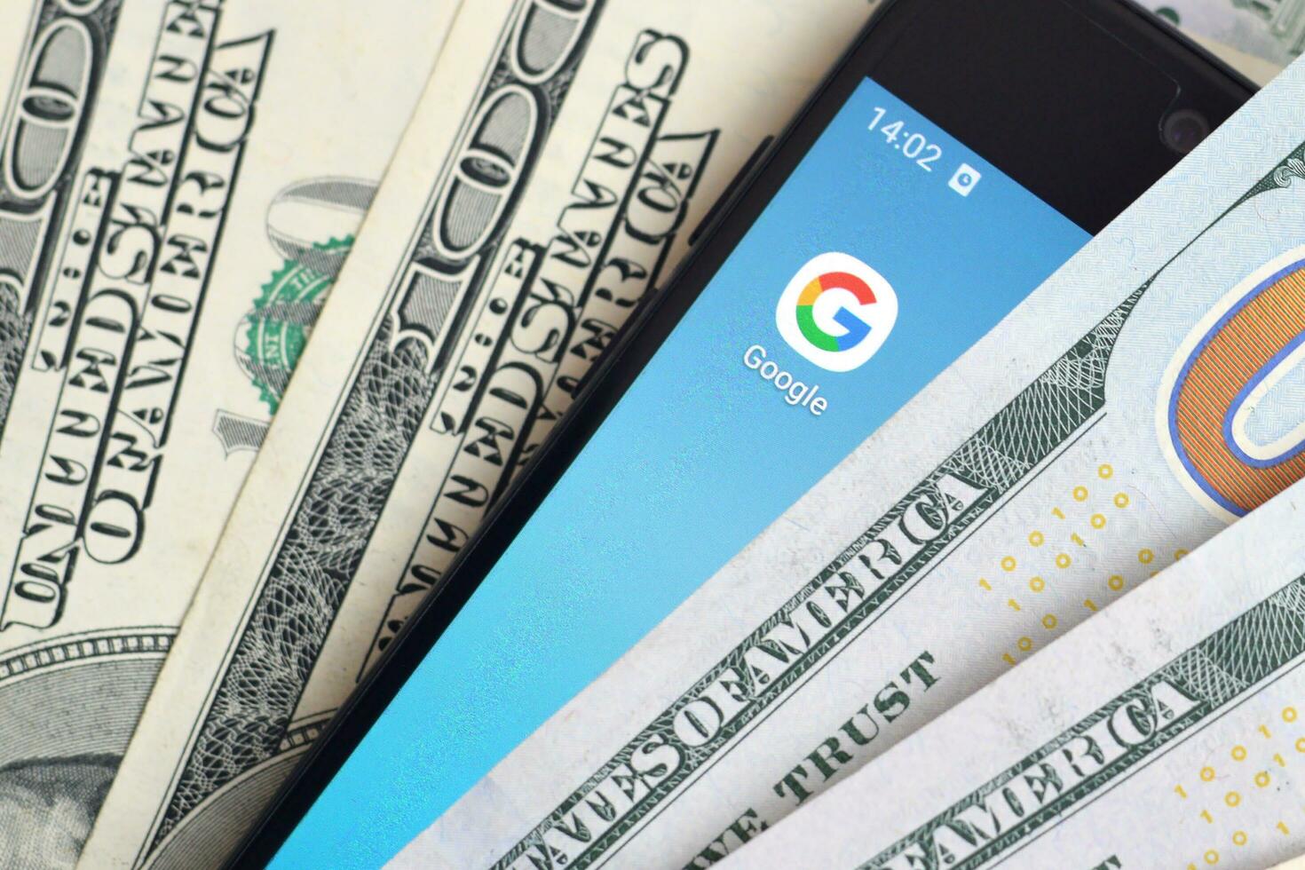 Smartphone screen with Google app and lot of hundred dollar bills. Business and social networking concept photo