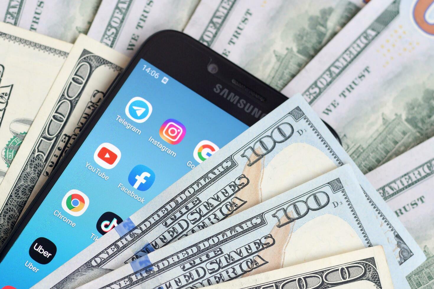Smartphone screen with many popular apps and lot of hundred dollar bills. Business and social networking concept photo