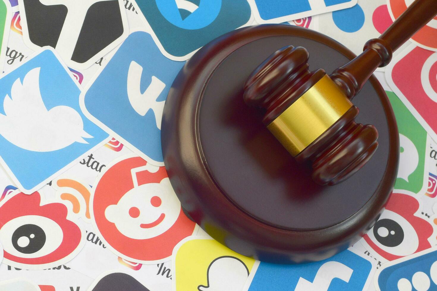 Wooden judge gavel lies on many paper logos of popular social networks and internet resources. Entertainment lawsuit concept photo