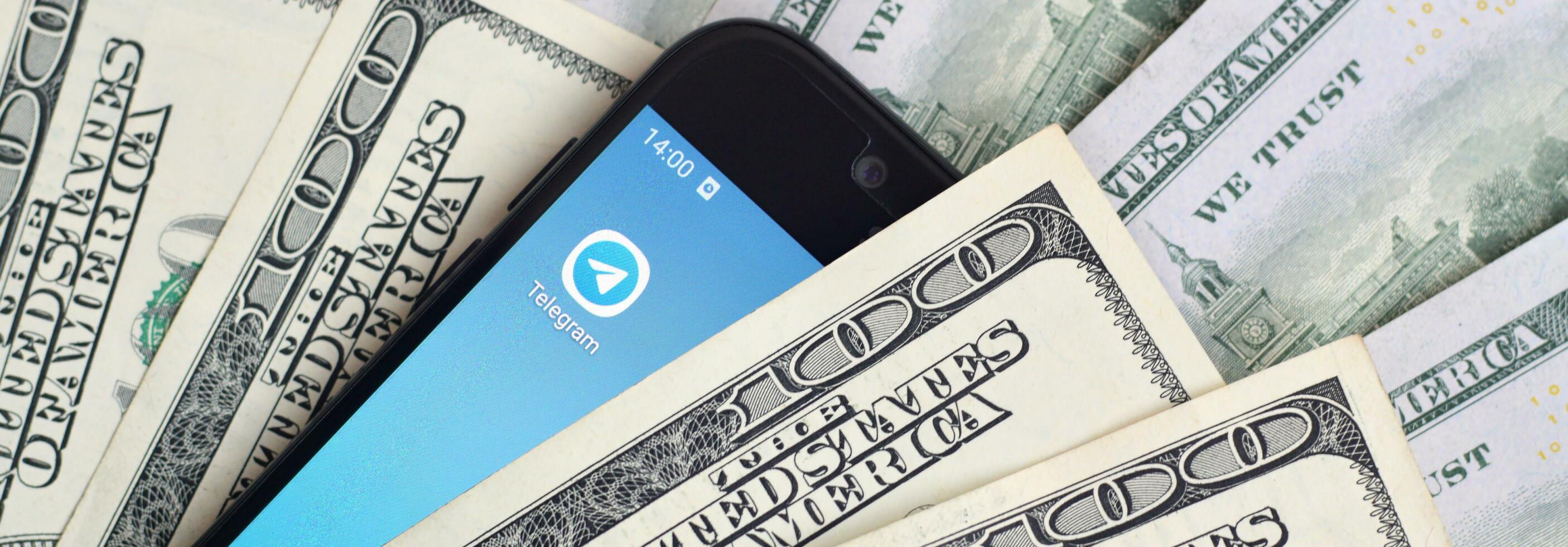 Smartphone screen with Telegram app and lot of hundred dollar bills. Business and social networking concept photo
