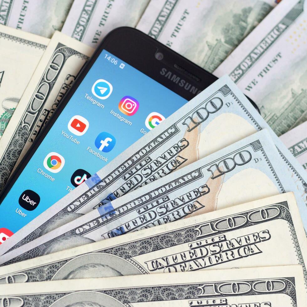 Smartphone screen with many popular apps and lot of hundred dollar bills. Business and social networking concept photo