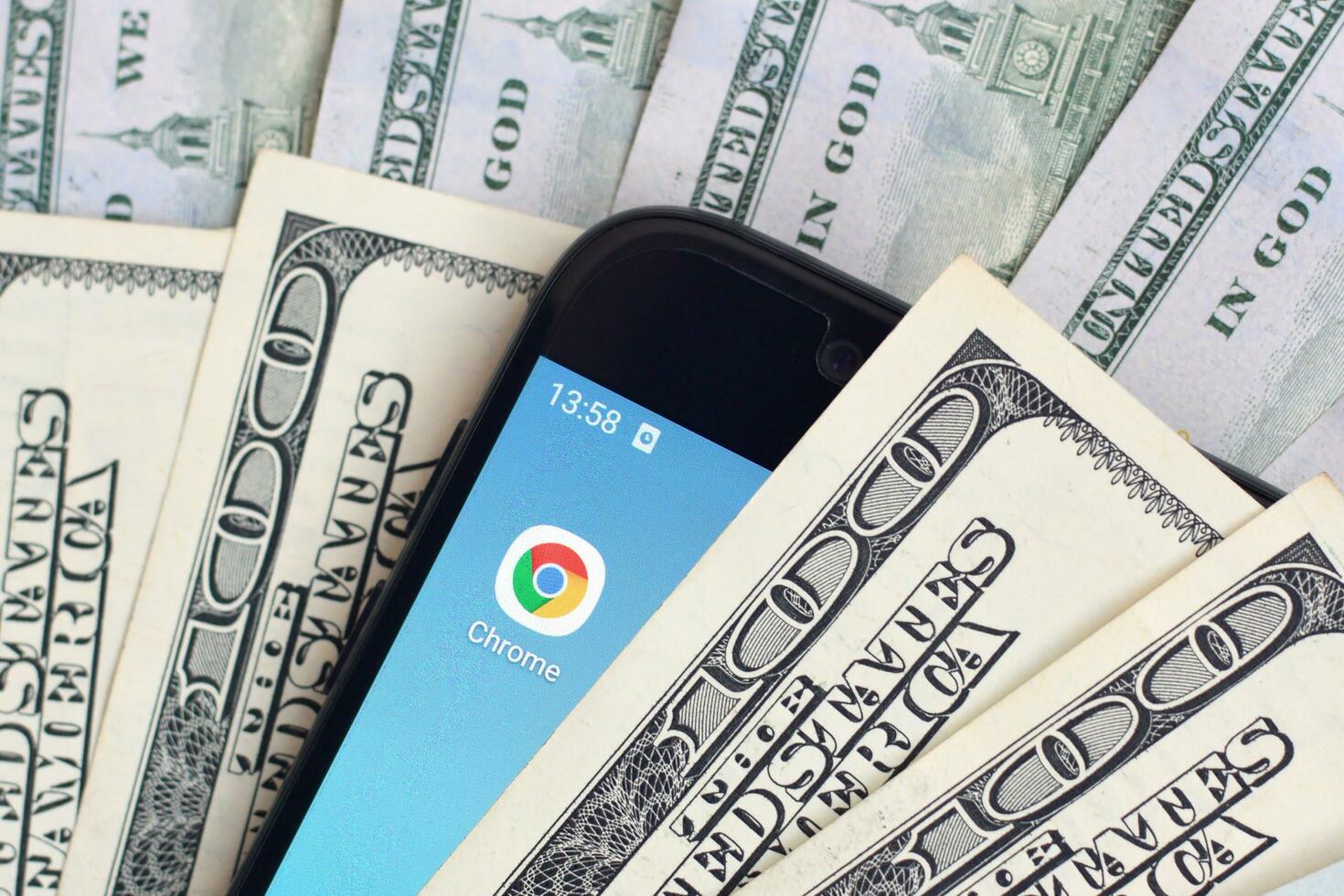 Smartphone screen with Google chrome app and lot of hundred dollar bills. Business and social networking concept photo