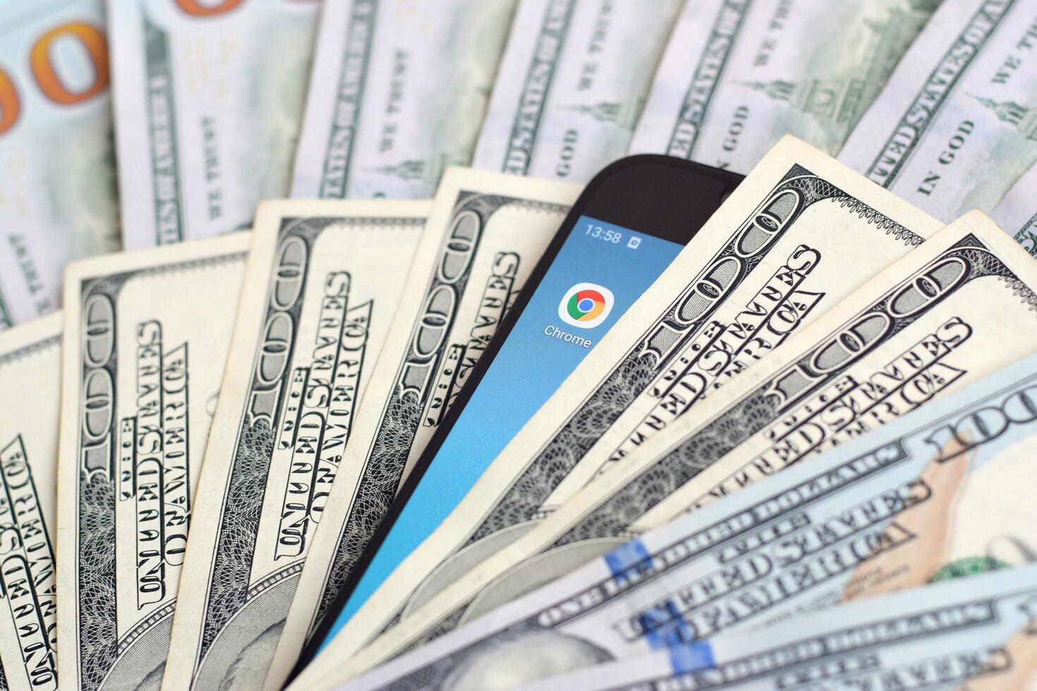 Smartphone screen with Google chrome app and lot of hundred dollar bills. Business and social networking concept photo