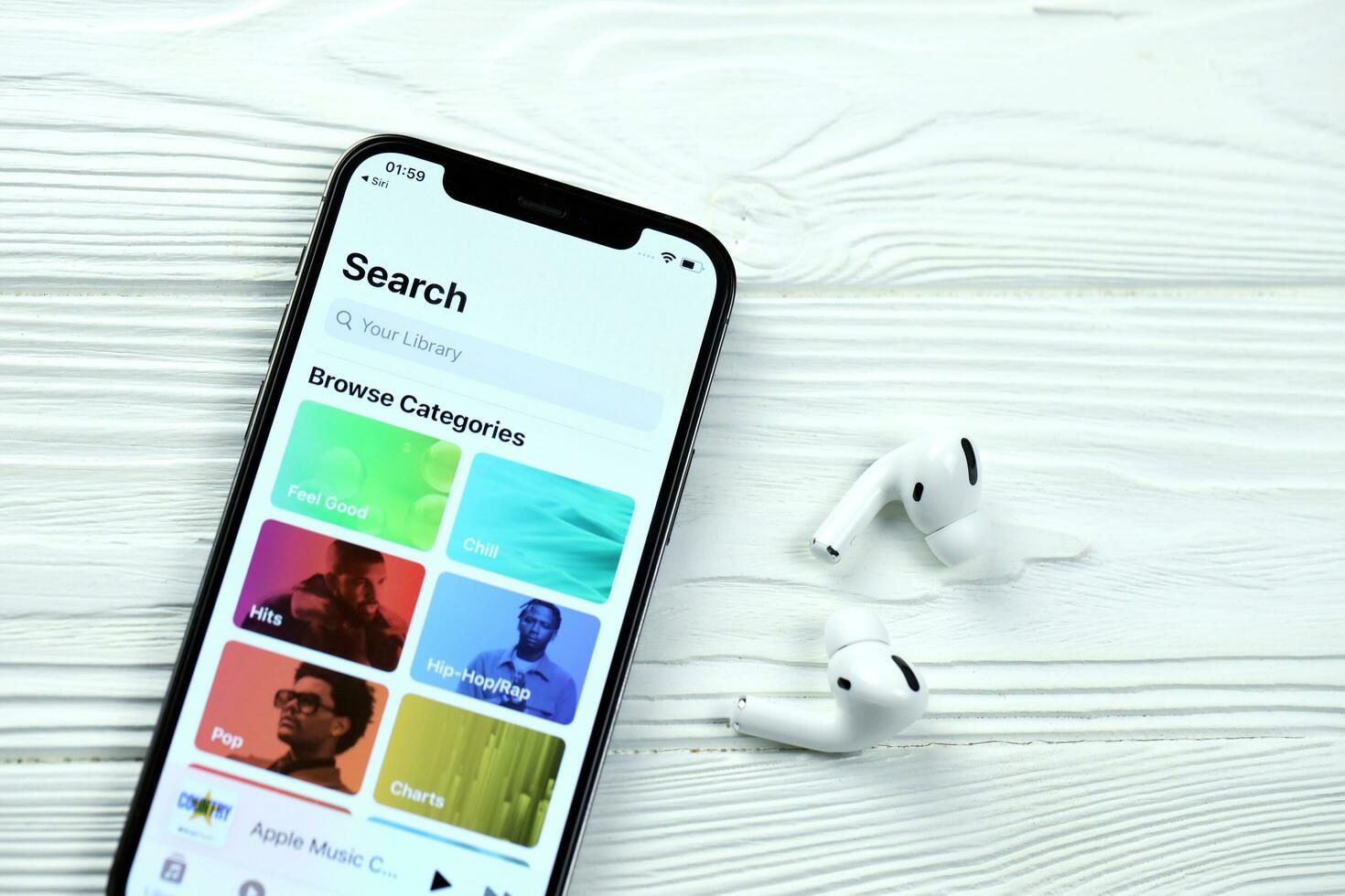 KHARKOV, UKRAINE - MARCH 5, 2021 Apple music icon and application from App store on iPhone 12 pro display screen with airpods pro on white table photo