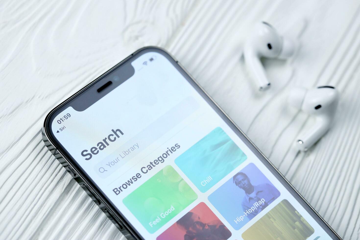 KHARKOV, UKRAINE - MARCH 5, 2021 Apple music icon and application from App store on iPhone 12 pro display screen with airpods pro on white table photo