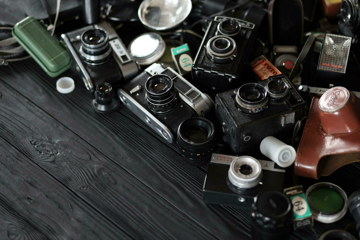 KHARKOV, UKRAINE - APRIL 27, 2021 Film photo cameras and another old retro photo equipment on black wooden table in photographer darkroom. Photographic gear from soviet union