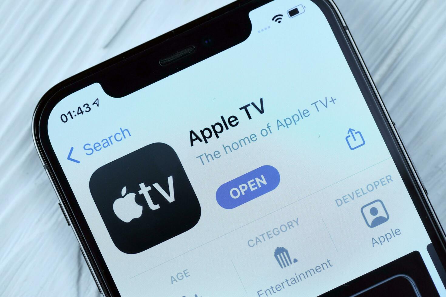 KHARKOV, UKRAINE - MARCH 5, 2021 Apple TV icon and application from App store on iPhone 12 pro display screen on white table photo
