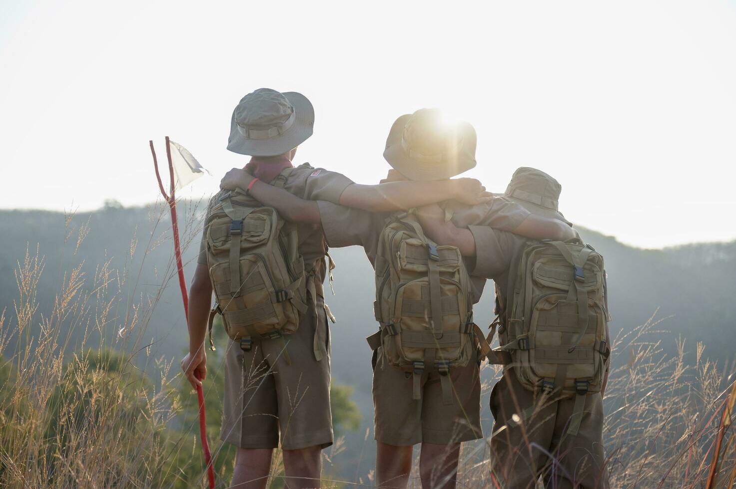 Boy Scouts team climbing with backpacks standing on mountain Boy Scouts rejoice at rock climbing success in Scout camp at sunset. Scout camp view. photo