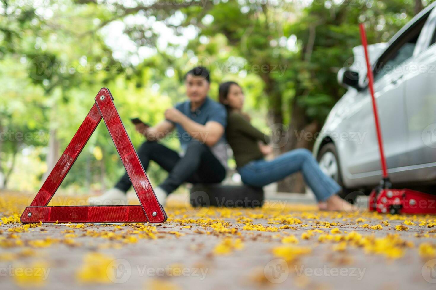 Asian couple using smartphone for assistance after a car breakdown on street. Concept of vehicle engine problem or accident and emergency help from Professional mechanic photo