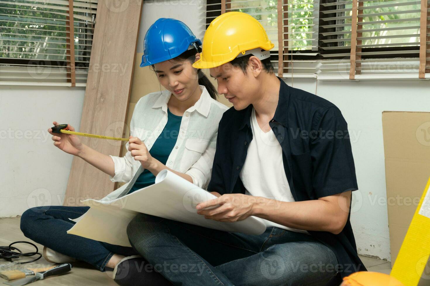 Happy Creative young Asian couple renovating house together and using a blueprint for renovation planning and how to   decorate and arrange the furniture on their new living room space photo