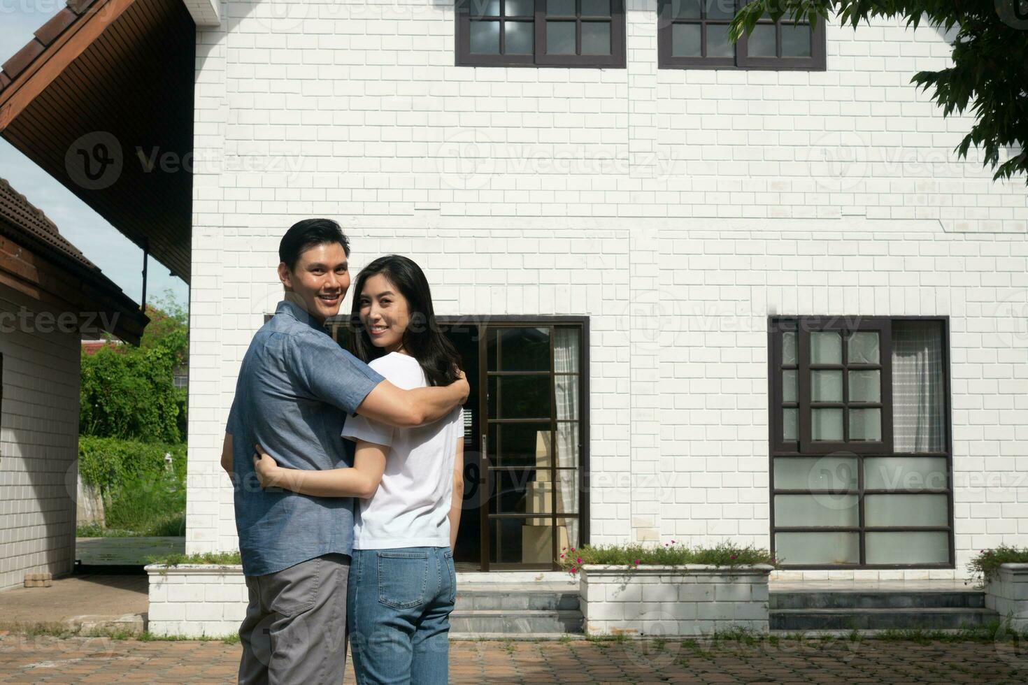 contento Pareja en frente de el nuevo hogar en Moviente en día, y comienzo un nuevo vida familia. concepto de dueño de casa y reubicación foto