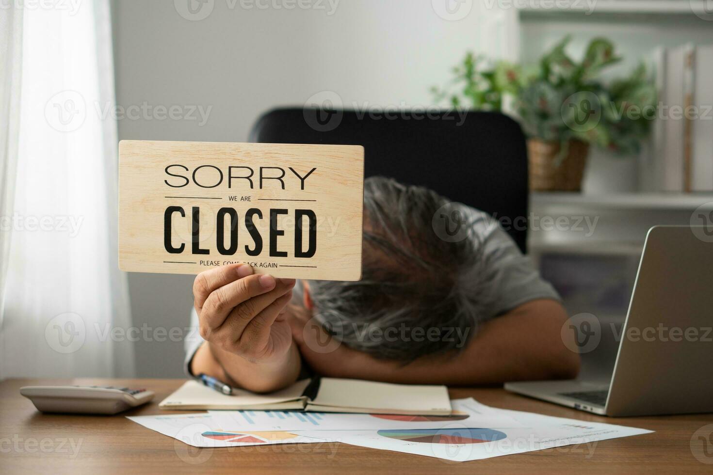 The owner of the business is stressed and disappointed. And holding a sign to close the business after the revenue and cost was raised and recognized the loss photo