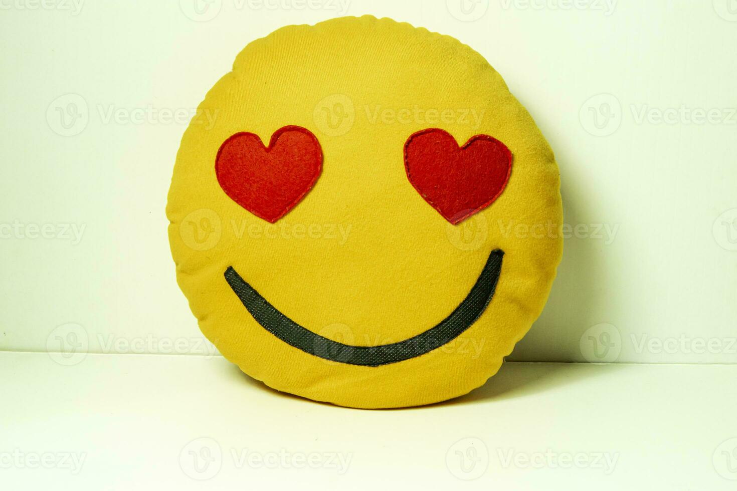 Yellow felt smiley with red hearts on it on a white background photo