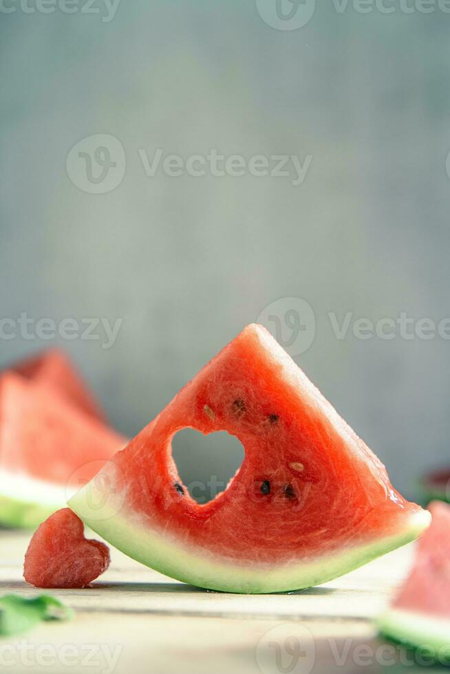 A cut piece of watermelon with a heart-shaped hole. Summer, joy, happiness, delicious food photo