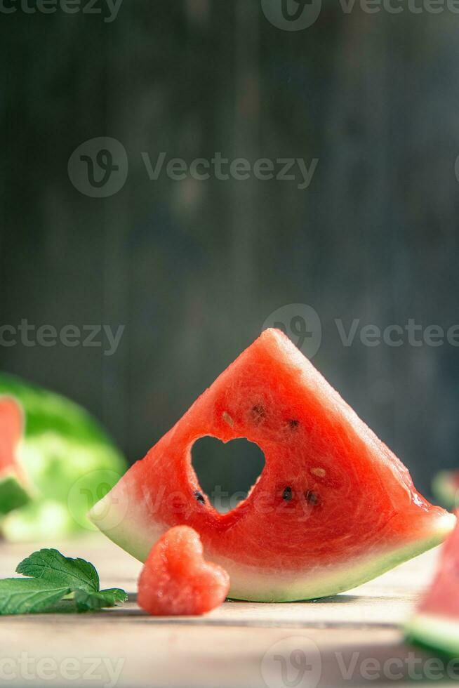 A cut piece of watermelon with a heart-shaped hole. Summer, joy, happiness, delicious food photo