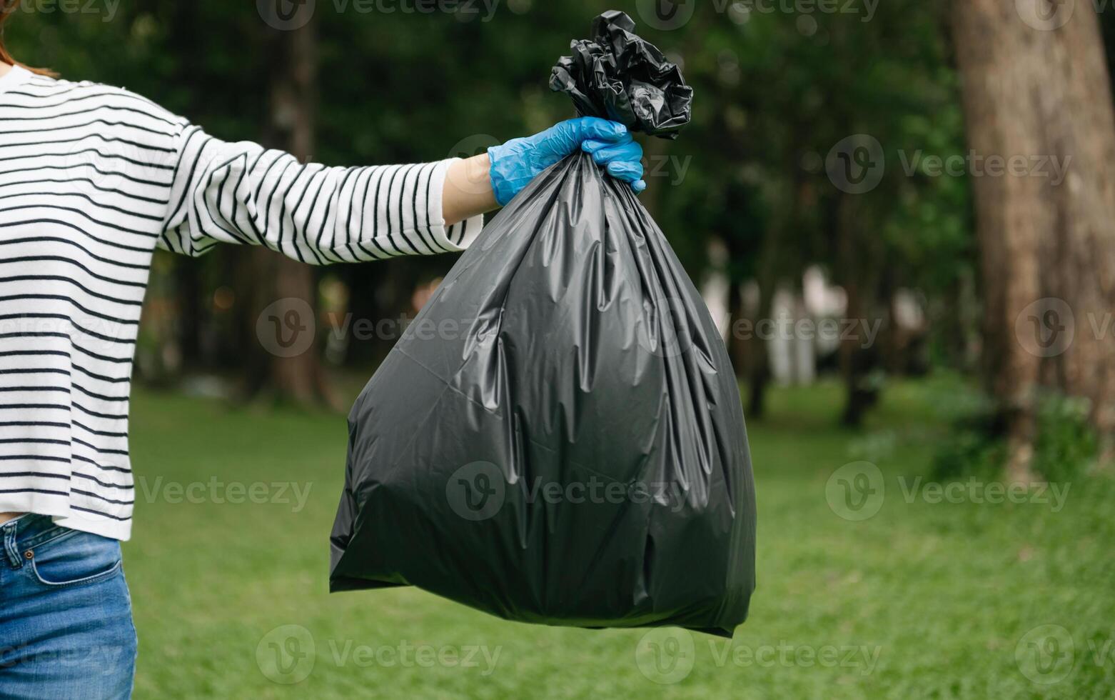 Hand holding garbage black bag putting in to trash to clean. Clearing, pollution, and plastic concept. photo