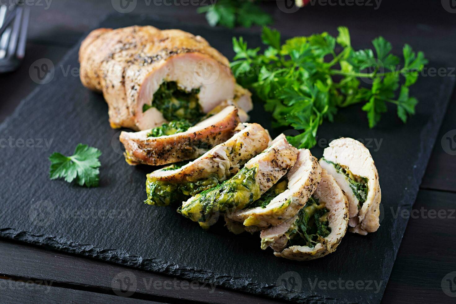 Roasted sliced Christmas roll of turkey with spinach and cheese on dark rustic background.  Festival food. photo