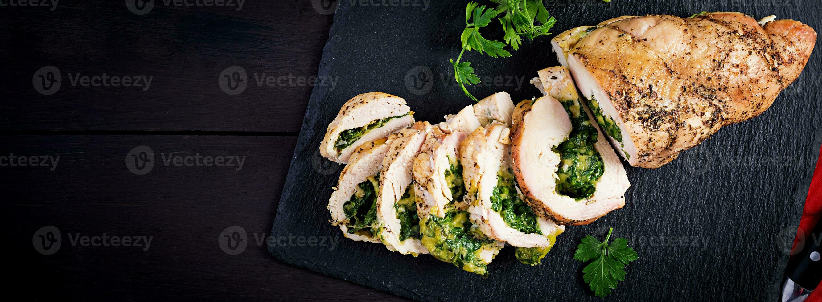 Roasted sliced Christmas roll of turkey with spinach and cheese on dark rustic background. Top view, copy space. Banner. Festival food. photo