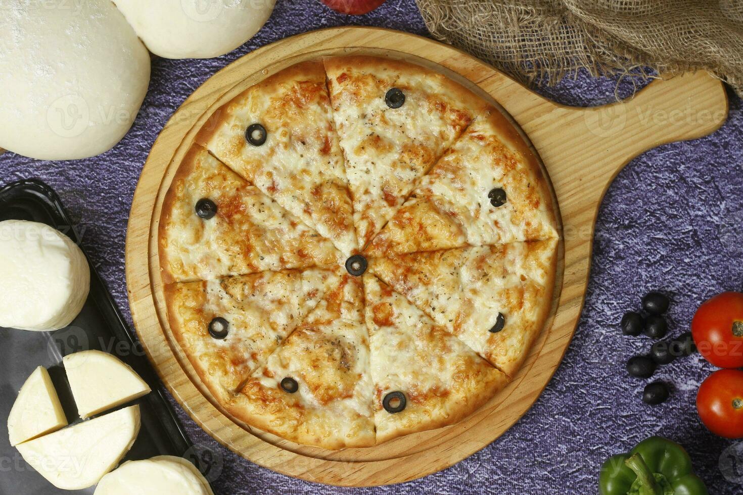 Flatbread pizza garnished with fresh angular on wooden pizza board top view dark stone background photo