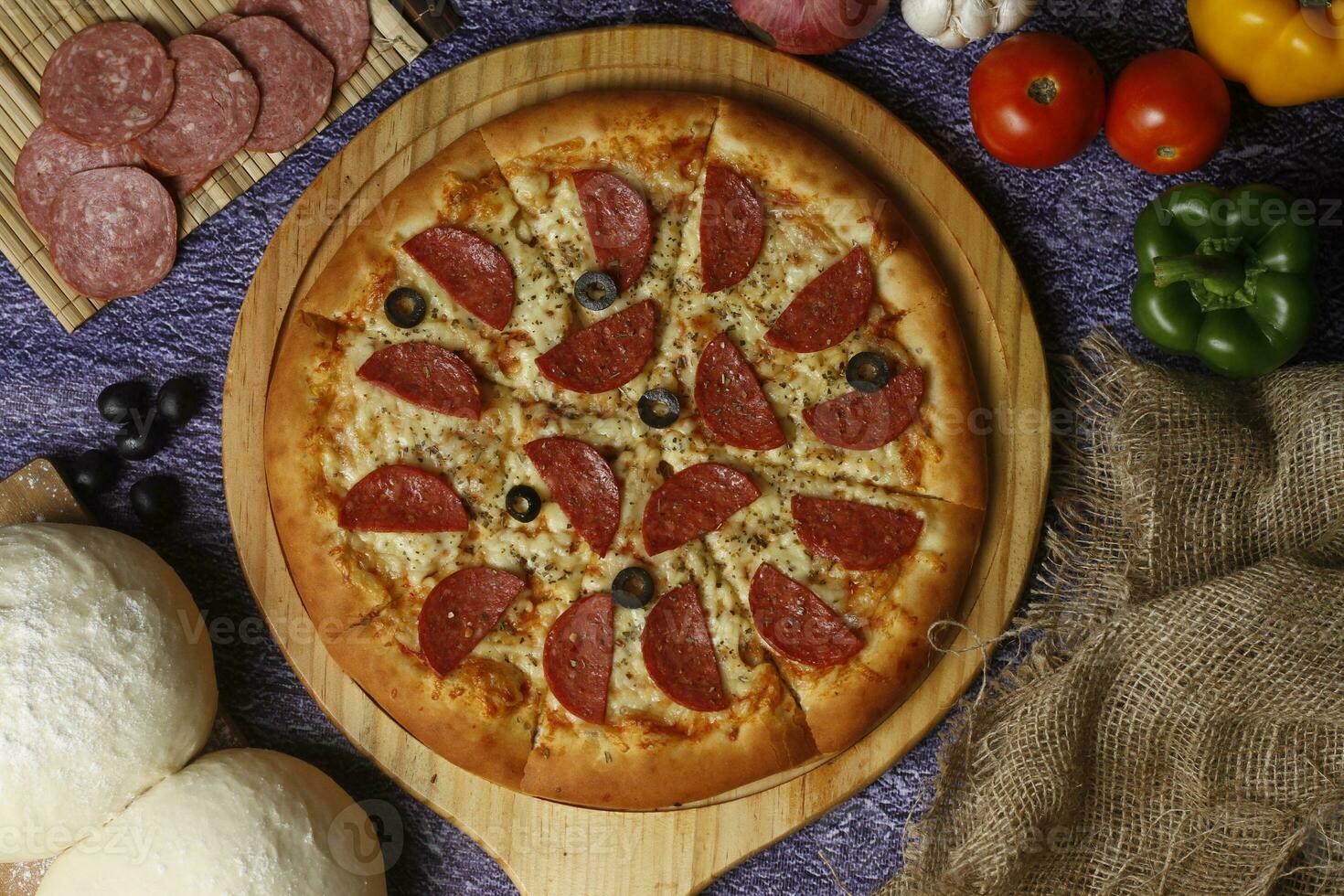 Flatbread pizza garnished with fresh angular on wooden pizza board top view dark stone background photo