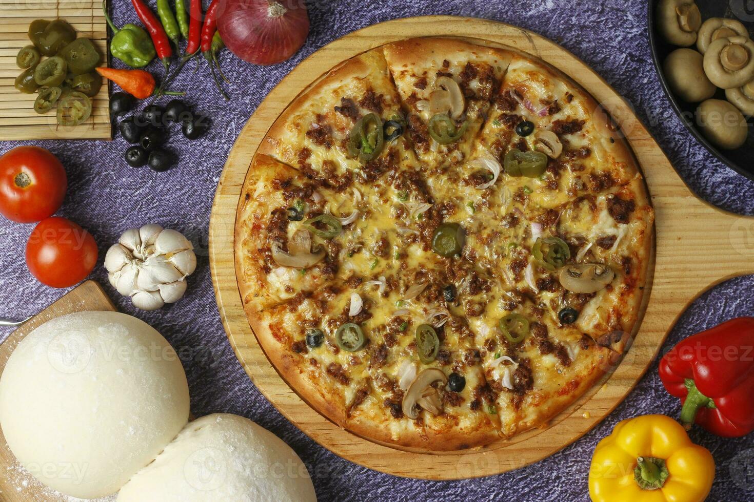 Flatbread pizza garnished with fresh angular on wooden pizza board top view dark stone background photo