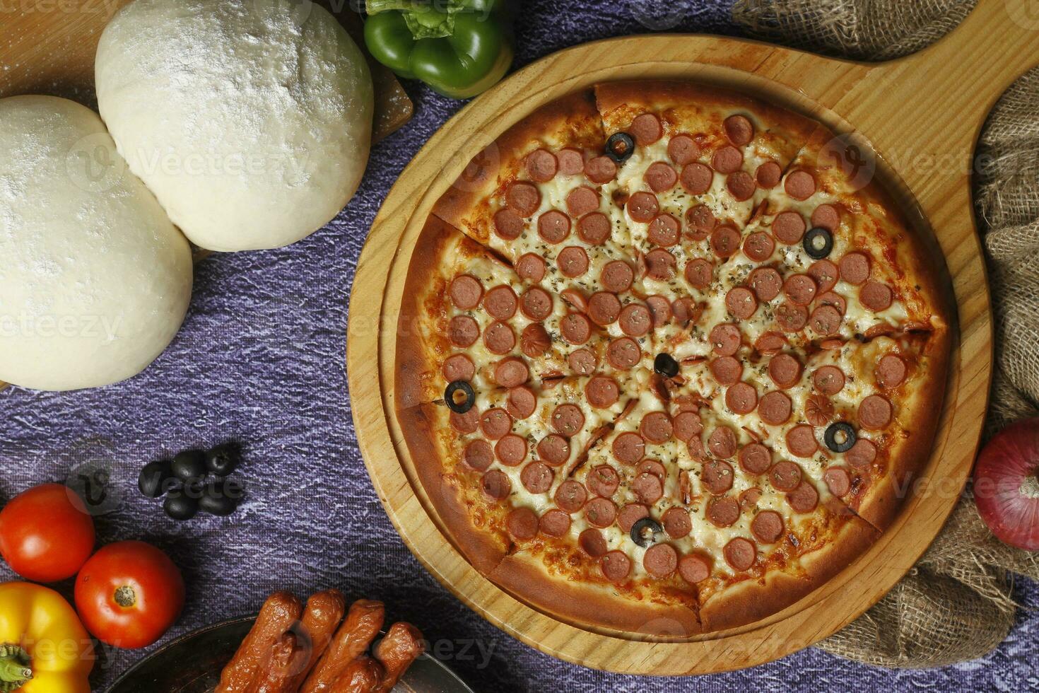 Flatbread pizza garnished with fresh angular on wooden pizza board top view dark stone background photo