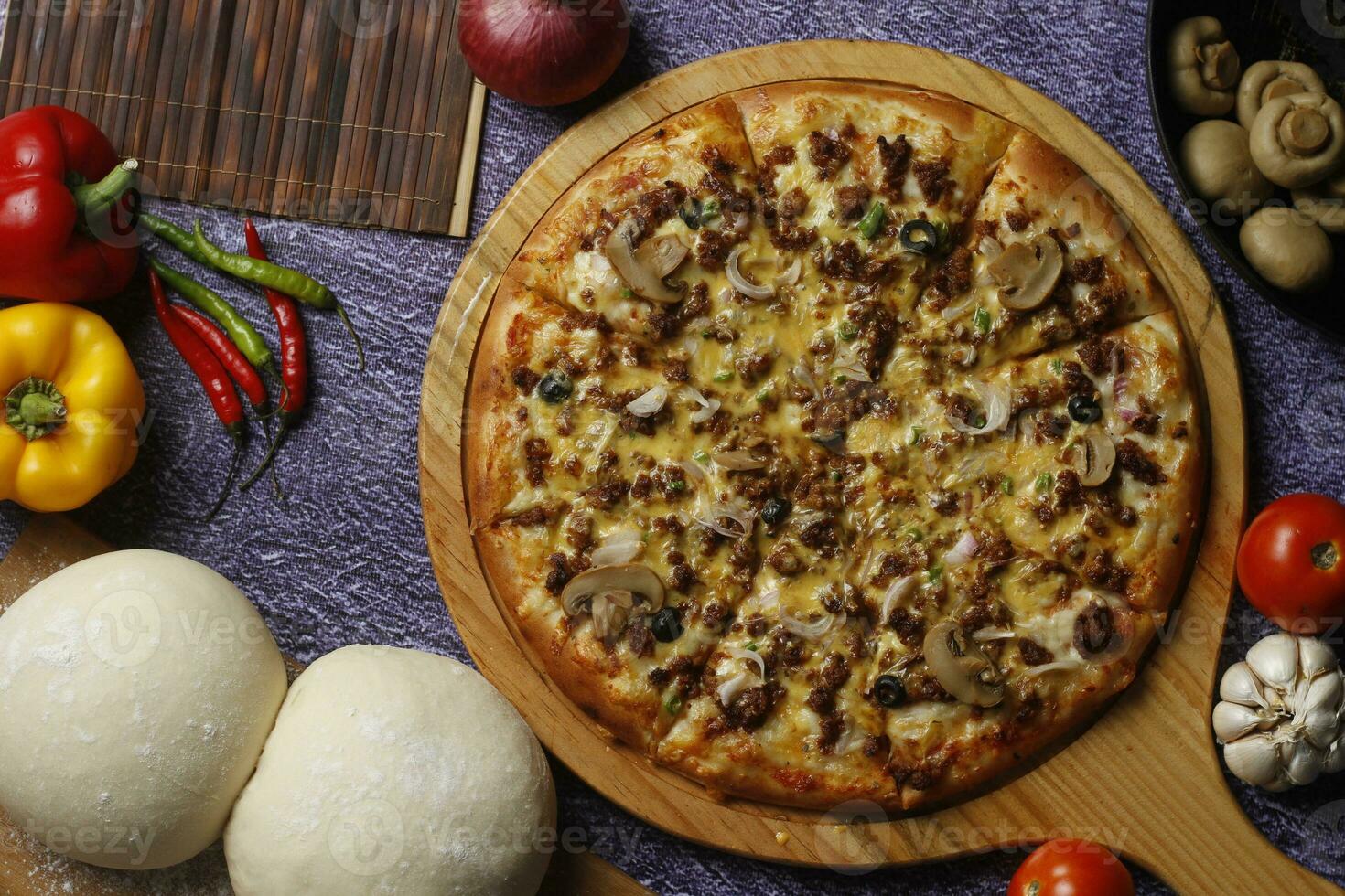 Flatbread pizza garnished with fresh angular on wooden pizza board top view dark stone background photo