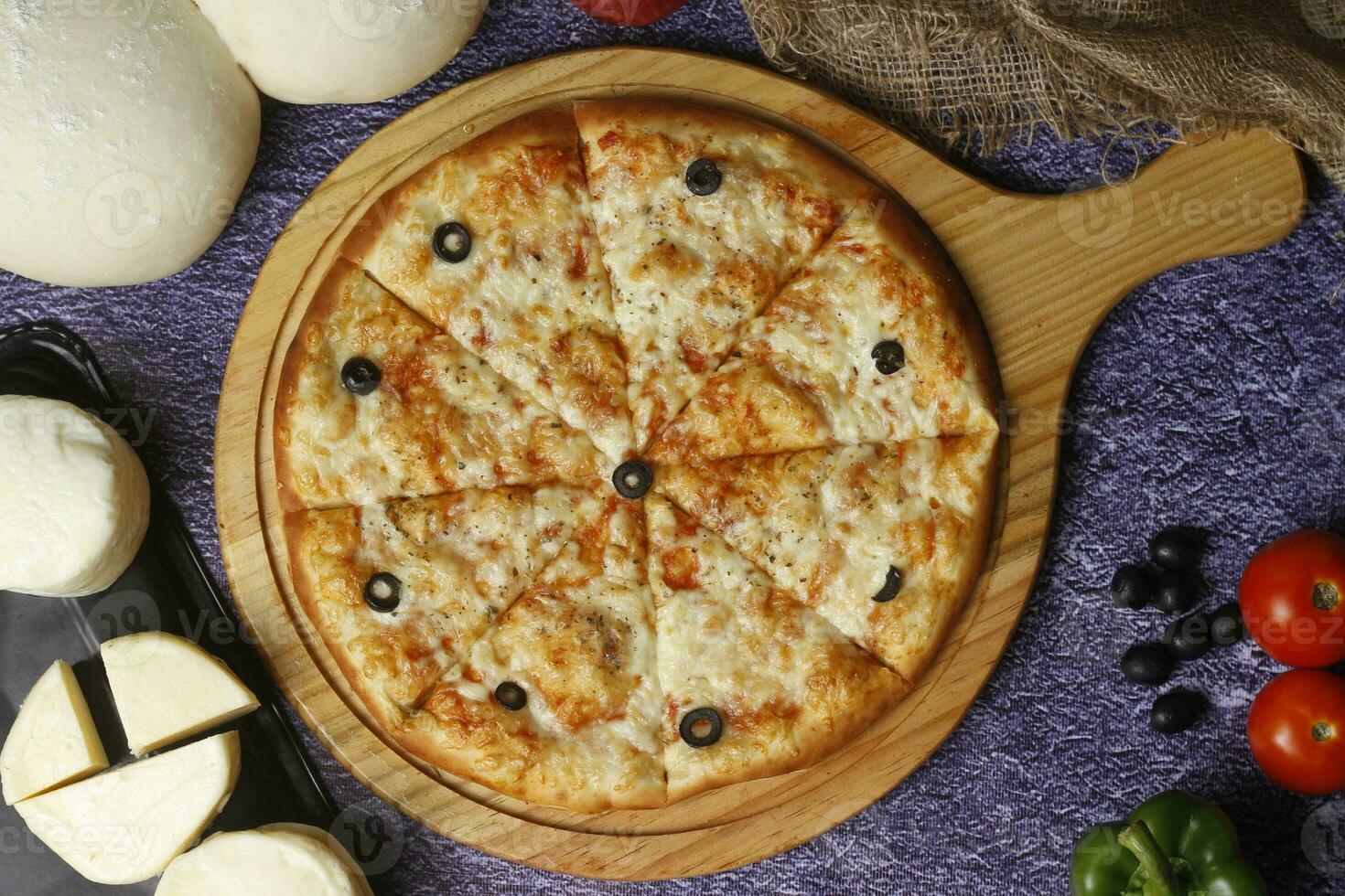 Flatbread pizza garnished with fresh angular on wooden pizza board top view dark stone background photo