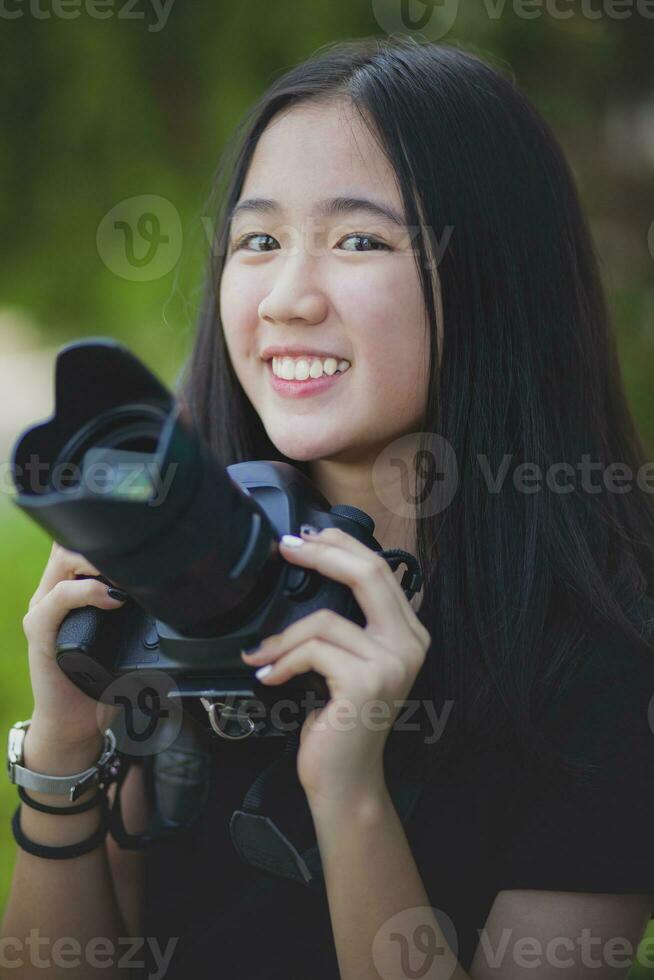 asian teenager toothy smiling face and holding dslr camera in hand photo