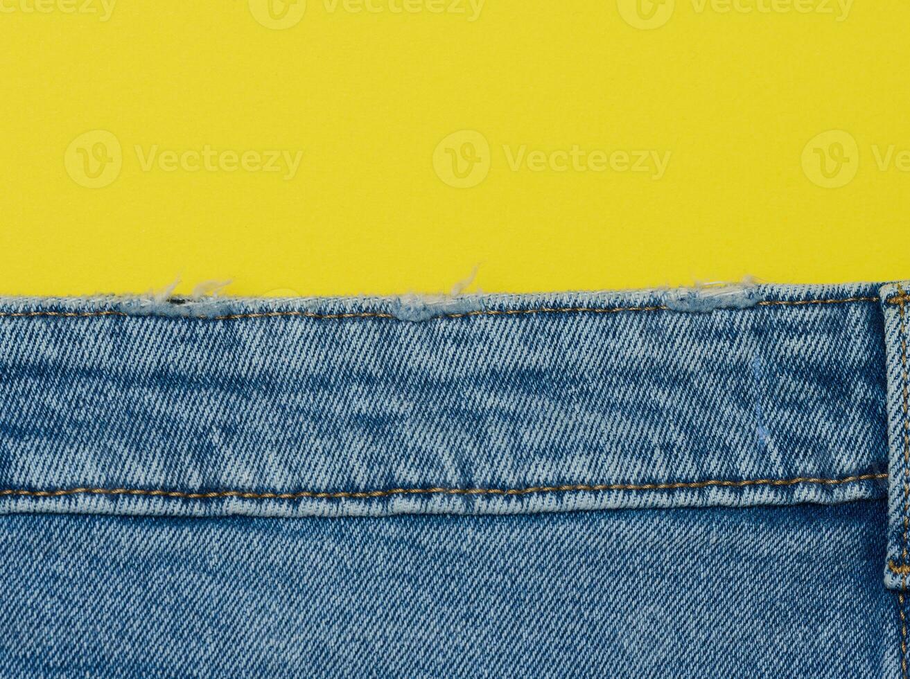 Blue jeans on a yellow background, copy space photo