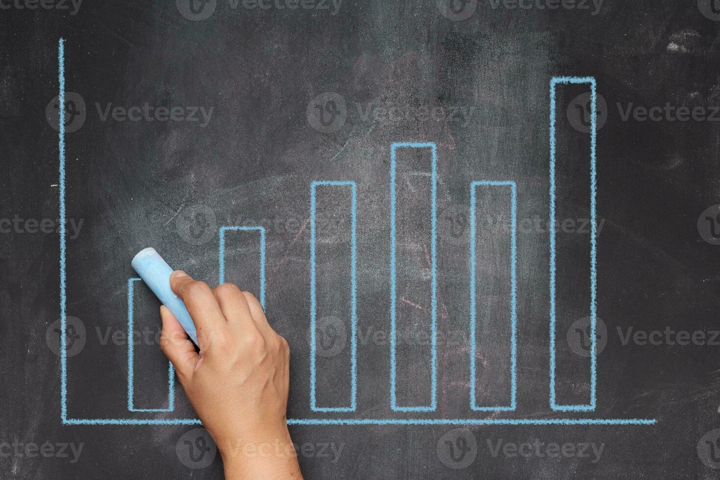 A woman's hand points to a graph with growing indicators drawn on a black chalkboard. photo