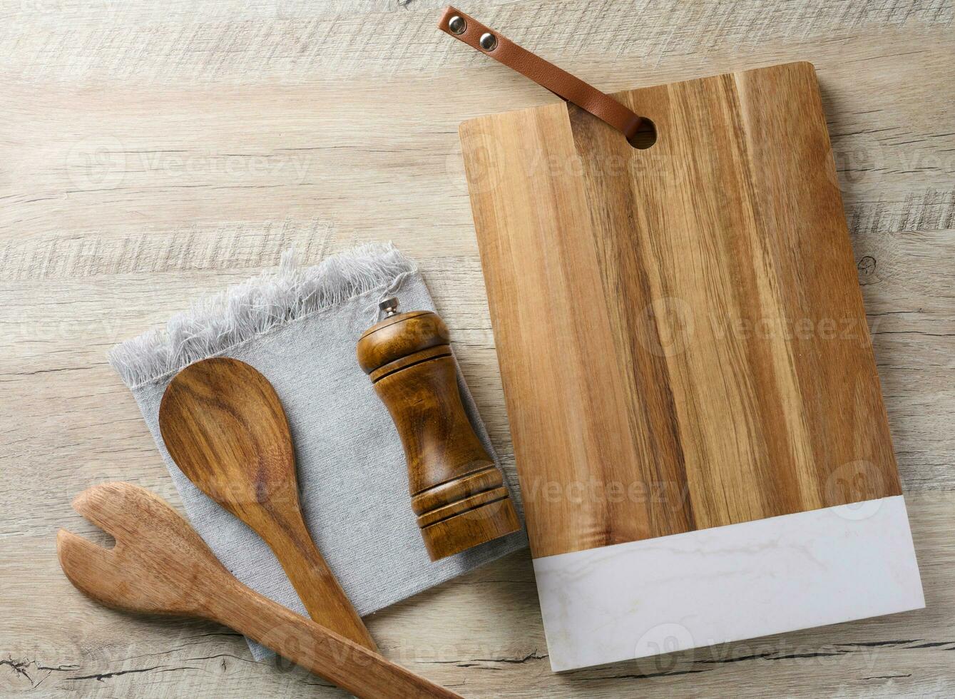 Empty rectangular wooden kitchen cutting board, empty bowl and wooden spoons on wooden table, top view photo