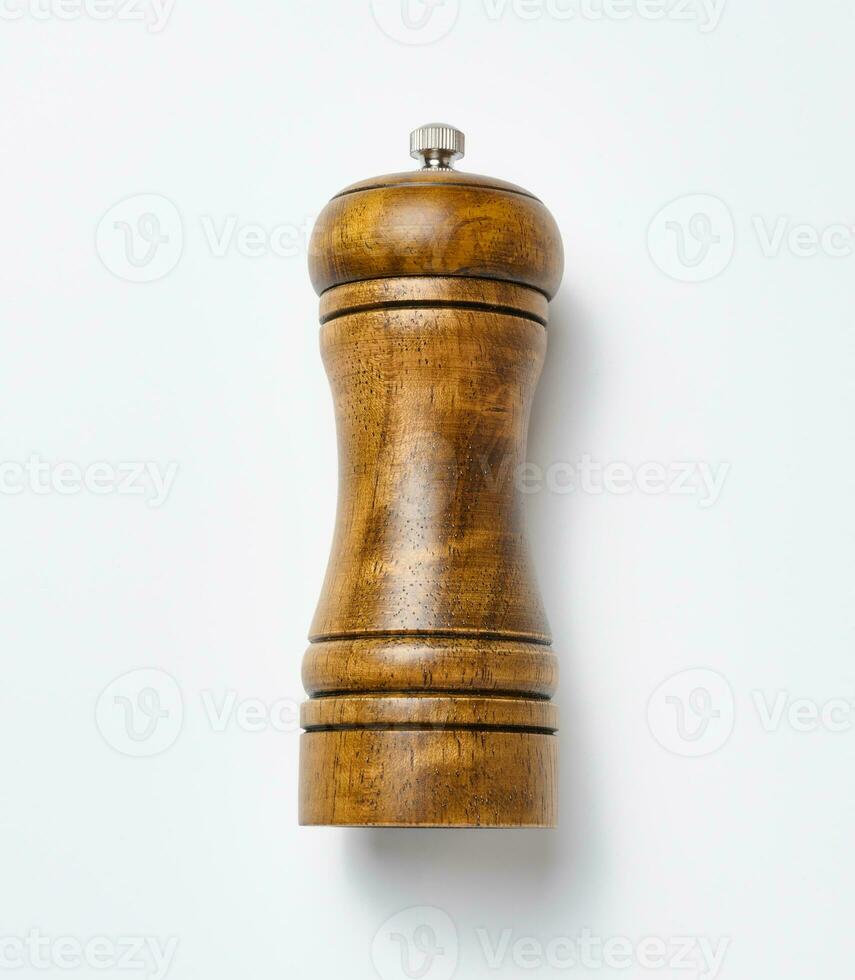 Wooden pepper mill on a white background, made of wood and has a metal handle on top photo