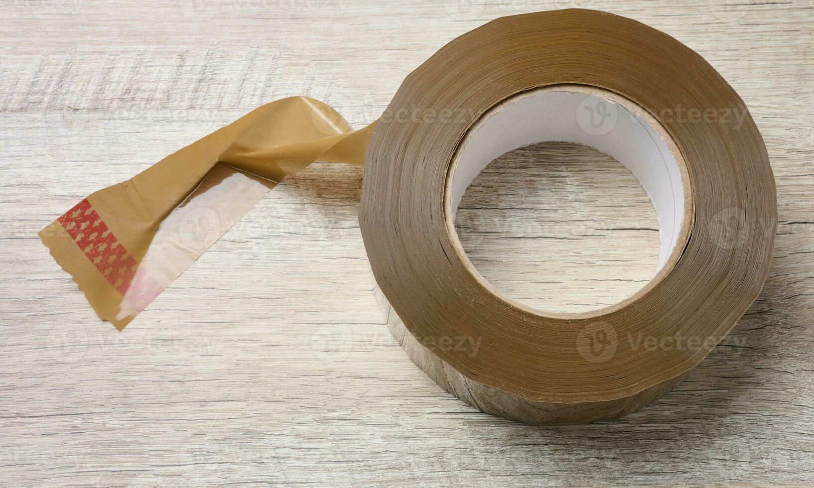 Roll of brown tape on a wooden table, top view photo