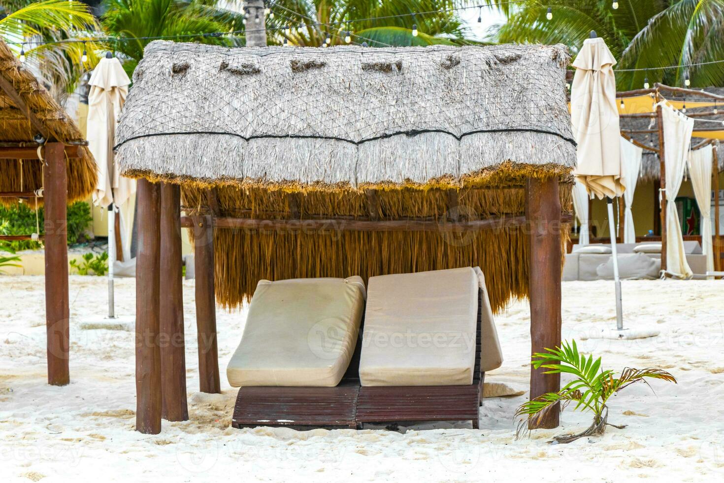 Palapa thatched roofs palms parasols sun loungers beach resort Mexico. photo