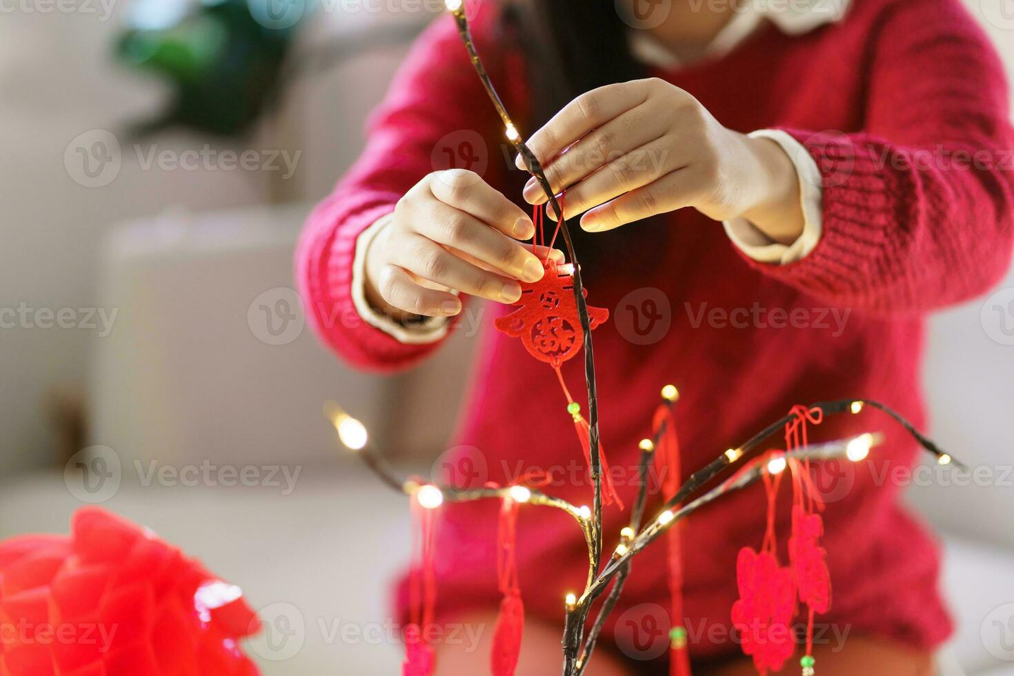 Asian Woman decorated house for Chinese New Year Celebrations. putting traditional pendant to the Chinese Lunar New Year for good luck. Chinese word means blessing photo