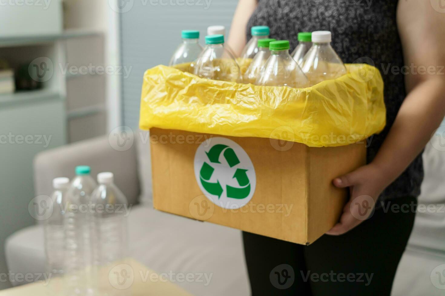 Home recycle eco green zero concept Woman throwing empty plastic bottle in recycling bin with yellow garbage bags at home. photo