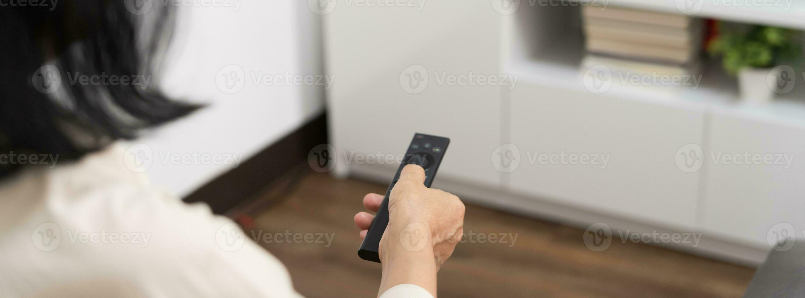Elderly woman Watching smart TV and using remote controller Hand holding television audio remote control Middle age Asian woman movie Television series spending time at home photo