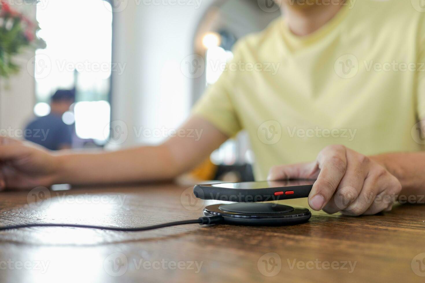 Charging mobile phone battery with wireless device in the table. Smartphone charging on a charging pad. Mobile phone near wireless charger. photo