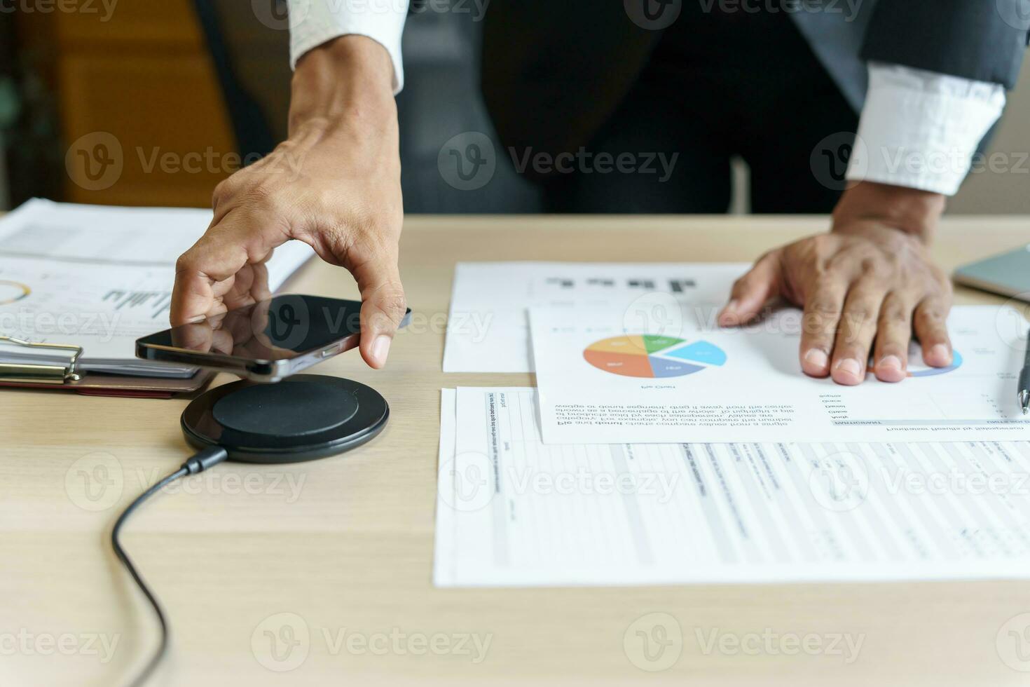 Charging mobile phone battery with wireless charging device in the table. Smartphone charging on a charging pad. Mobile phone near wireless charger Modern lifestyle technology concept photo