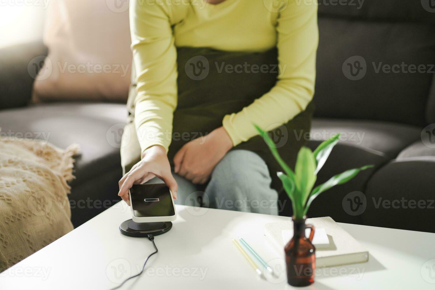 Charging mobile phone battery with wireless charging device in the table. Smartphone charging on a charging pad. Mobile phone near wireless charger Modern lifestyle technology concept. photo