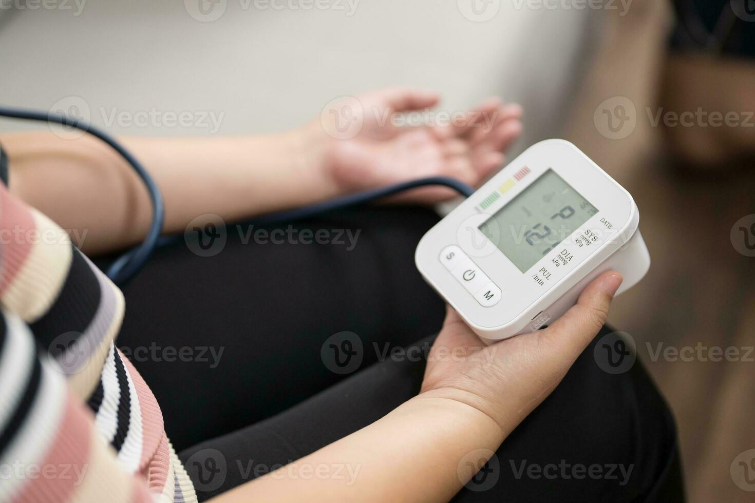 woman Overweight plus size self checks measuring blood pressure and heart rate tonometer self checkup at home photo